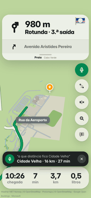 A conduzir na Praia, pergunta em voz alta “a que distância fica Cidade Velha”; a resposta: Cidade Velha · 16 km · 27 min